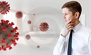 Young thoughtful businessman looks on coronavirus cells.