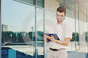 Young thoughtful businessman writing in notepad