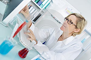 Young thoughtful female chemist working in lab