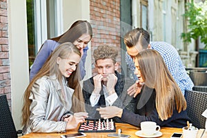 Young thoughtful friends having a chess competition on a cafe background. Friendship concept.