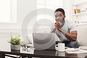 Young thoughtful man at home messaging online on laptop photo