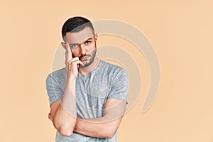 Young thoughtful man thinking and looking to camera with copy space, isolated on studio background