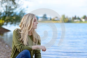 Young thoughtful woman sitting by lake