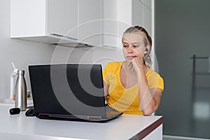 Young thoughtful woman working with laptop from home