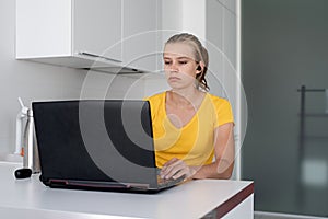 Young thoughtful woman working with laptop from home