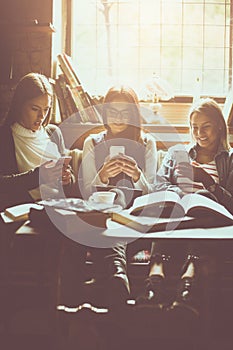 Young three students girls at cafe using smart phone.