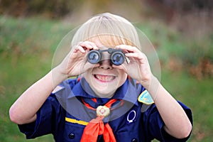 Young Tiger Cub Scout Smiling at Camera Through Binoculars