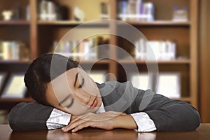 Young tired asian woman sleeping on desk