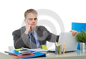 Young tired businessman overworked and upset looking worried sitting at computer desk