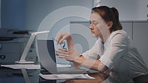 Young tired businesswoman looking unhappily at laptop display analyzing financial data in office