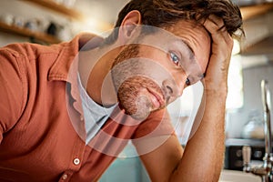 Young tired caucasian businessman working from home alone. One stressed businessman looking unhappy while working at