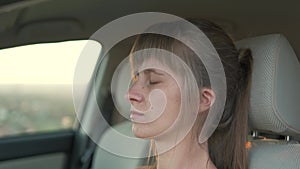 Young tired female driver resting behind the wheel of her car during road trip.