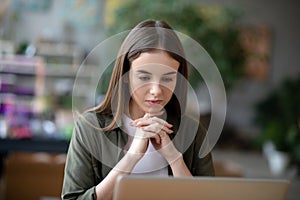 Young tired girl looking at laptop screen.