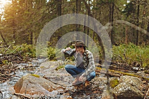 Young tired hiker drinking water from a pure mountain stream