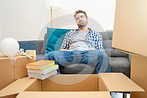 Young tired man after relocation surrounded by large boxes