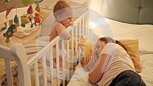 Young tired mother fell asleep next to her baby crying in bed. Concept of parenting, parent fatigue and children