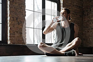 Young tired sportsman sitting on the floor