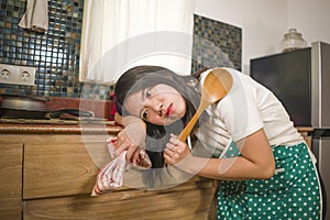 Young tired and stressed Asian Korean woman in cook apron working leaning on kitchen sink lazy in moody and upset face