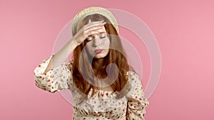 Young tired woman is dissatisfied, unhappy. PInk studio portrait of girl, she exhales from heat or stuffiness, waves