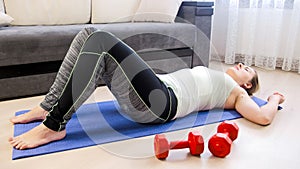 Young tired woman lying on floor after doing sit-ups