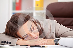 Young tired woman at office desk sleeping with eyes closed, sleep deprivation and stressful life concept