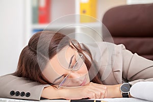 Young tired woman at office desk sleeping with eyes closed, sleep deprivation and stressful life concept