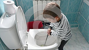 Young toddler boy cleans and disinfects the bathroom and toilet. Fun child's play at home. Little helper concept