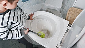 Young toddler boy cleans and disinfects the bathroom and toilet. Fun child& x27;s play at home. Little helper concept.