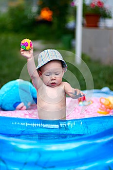 Young toddler boy playing in kiddie pool with rubber ball