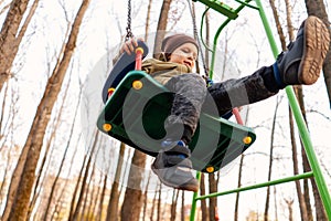 Young toddler boy swinging on a swing