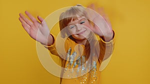 Young toddler school girl kid smiling friendly gesturing hello or goodbye, welcoming, waving hands