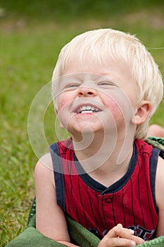 A young toddler smiles big in the yard