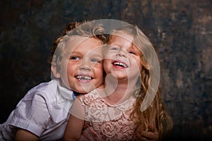 Young toothless boy and little girl laughing against blue and gold wall. Emotions. Copy space