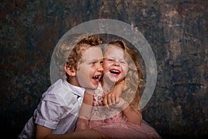 Young toothless boy and little girl laughing against blue and gold wall. Emotions. Copy space