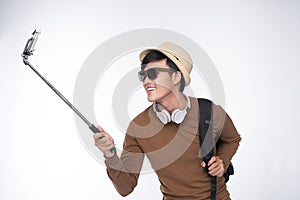 Young tourist asian man taking selfie picture over grey background