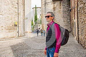 A young tourist with a backpack standing and smiling in the cent