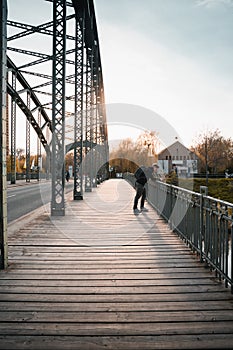 Young tourist with a backpack walking alone on a wooden bridge during the sunset
