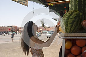 Young tourist buying one of the best juices and smoothies of Marrakech fresh fruit sold in the Jemaa el Fna square