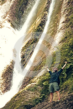 Young tourist camping with backpack near a waterfall in forest.