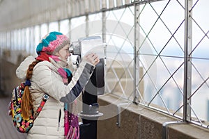 Young tourist enjoying the view of New York though binoculars