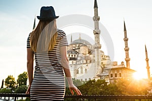 A young tourist girl with a beautiful figure looks from the hotel terrace to the world famous blue mosque Sultanahmet in