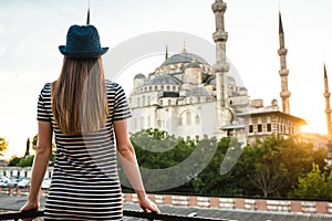 A young tourist girl with a beautiful figure looks from the hotel terrace to the world famous blue mosque Sultanahmet in