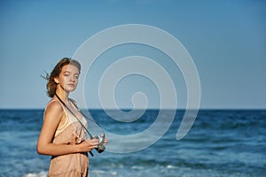 Young tourist girl with a camera on the coast.