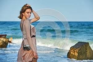 Young tourist girl with a camera on the coast.