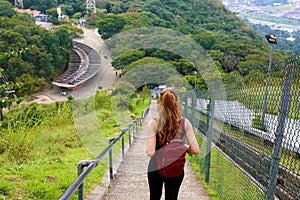 Young tourist girl carrying backpack descending stairs and enjoying the view from Jaragua Peak, Brazil