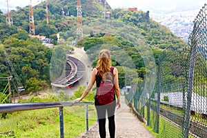 Young tourist girl carrying backpack descending stairs and enjoying the view from Jaragua Peak, Brazil