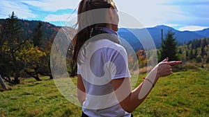 Young tourist girl dances in a clearing against the backdrop of the mountains. Autumn trek to the Carpathians. High