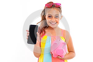 Young tourist girl with a phone with a pink piggy bank mockup on a white background with copy space