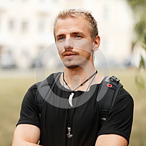 Young tourist man with a backpack in a black stylish T-shirt