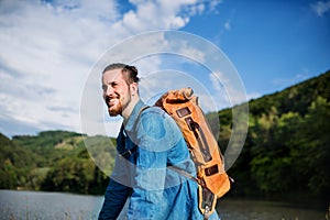 Young tourist man traveller with backpack standing in nature, resting.